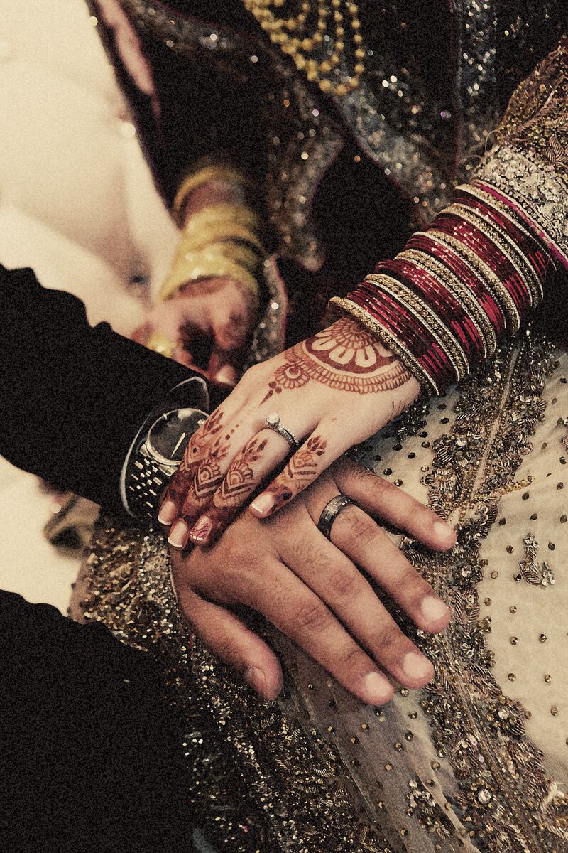 The couple's hands, mehndi and wedding rings