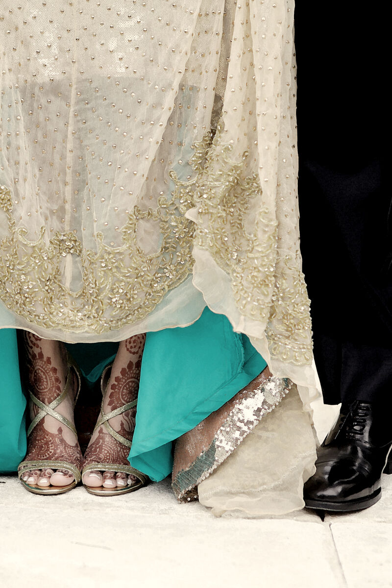 Ivory and aqua lehenga hem beside the groom's polished shoes