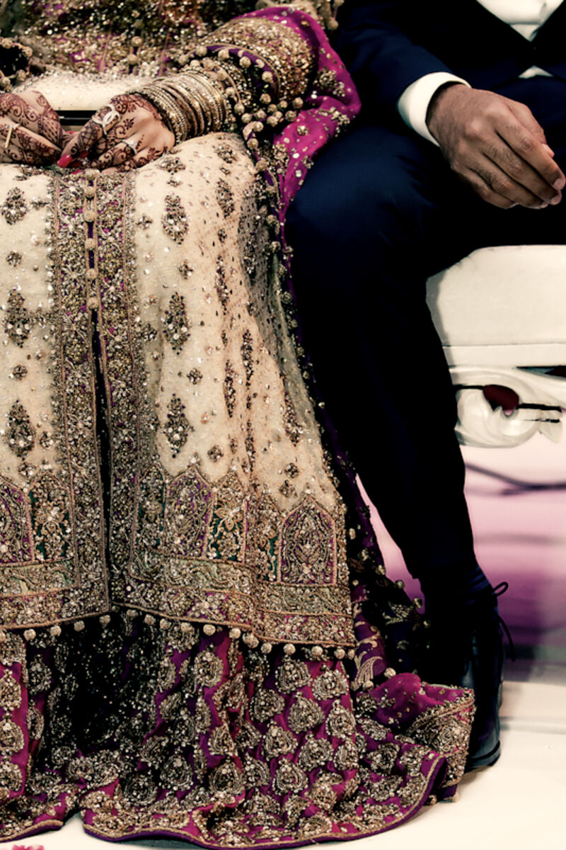 Bride in a gold-embroidered lehenga seated beside the groom