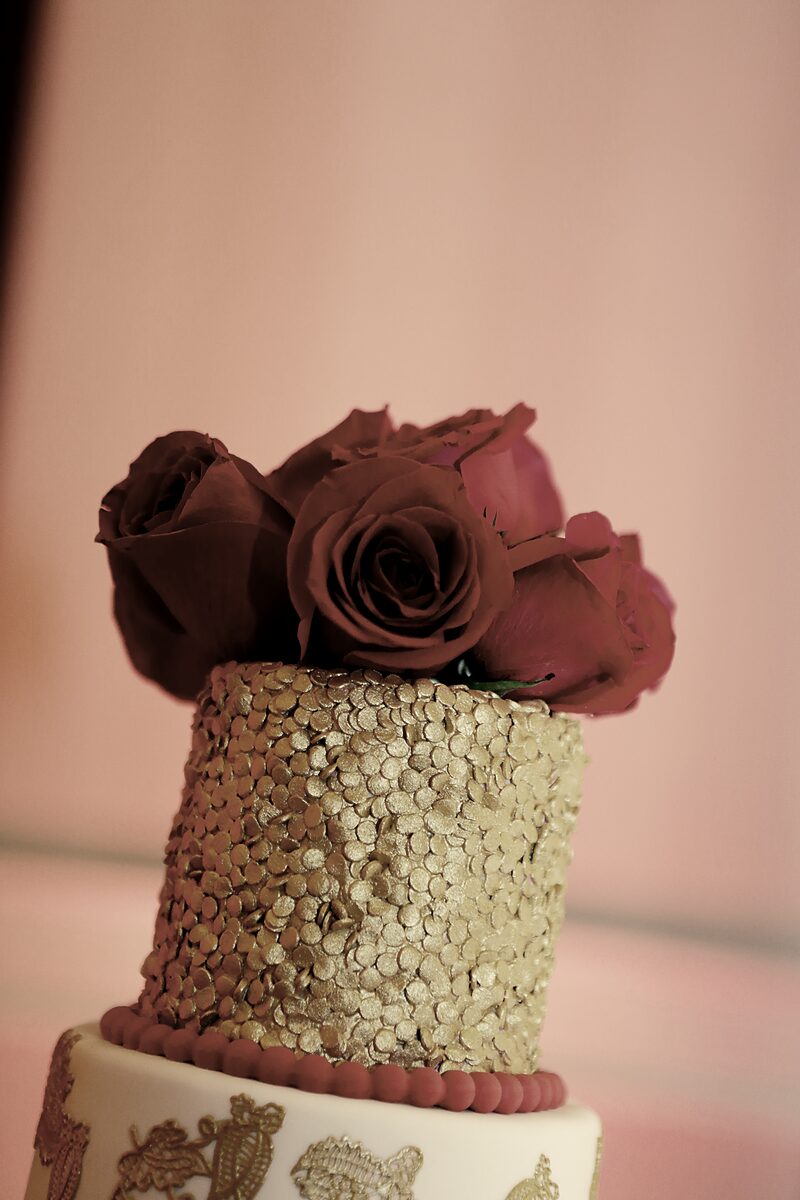 Gold-sequined wedding cake crowned with deep red roses