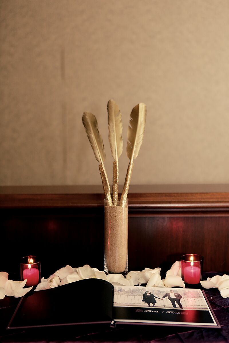 Gilded quills beside the wedding guestbook